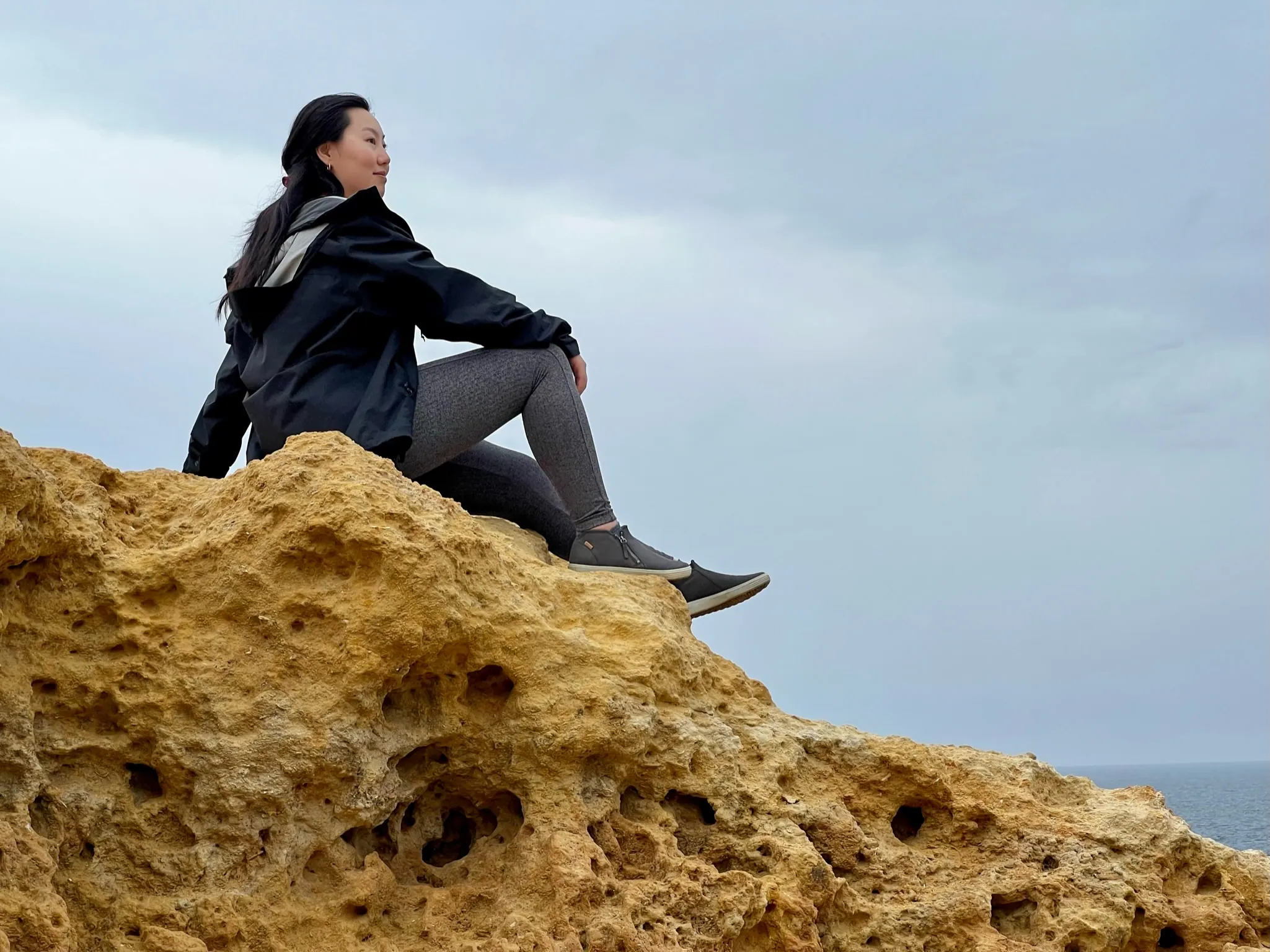 April sitting on rocks in front of a blue sky, looking over the horizon.